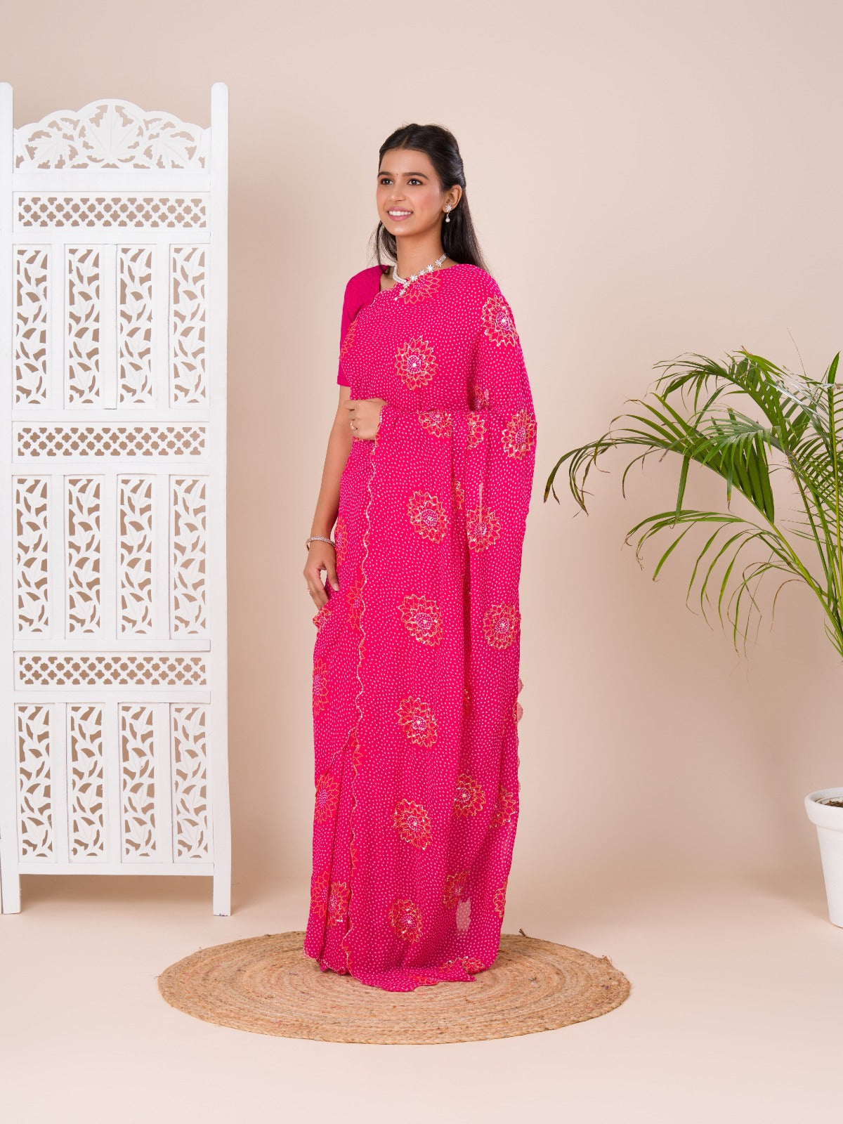 A pink saree with bandhani pattern and aari tari work