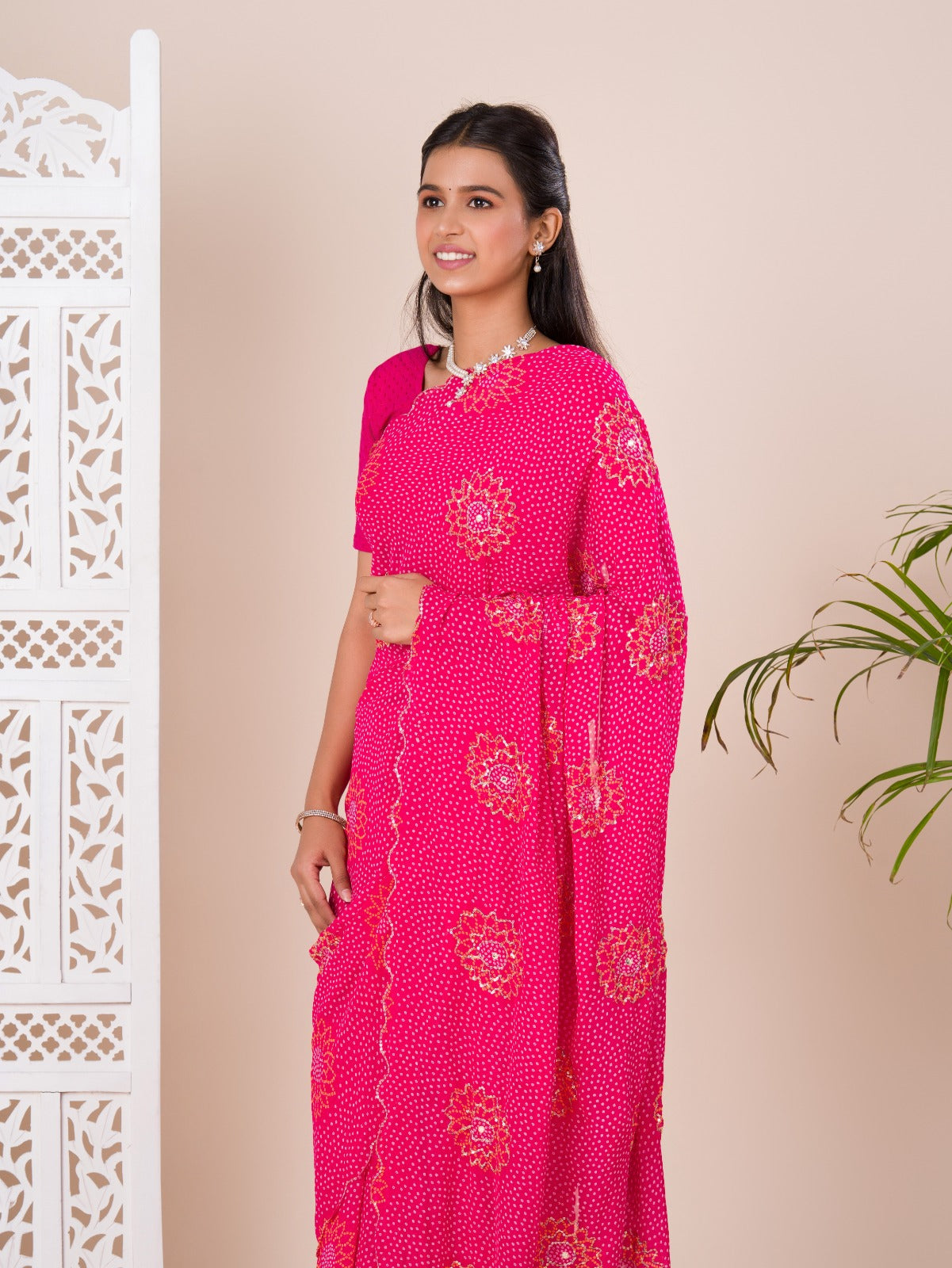 A pink saree with bandhani pattern and aari tari work