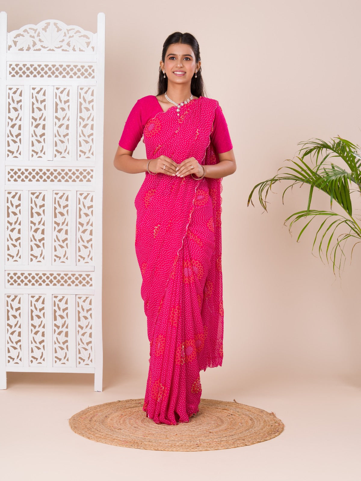 A pink saree with bandhani pattern and aari tari work