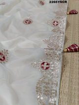 A cream-colored tissue silk saree with Bollywood-style embellishments and gotapatti work, including floral patterns and traditional border designs.
