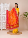 Atraditional Rajasthani Bandhani Chunri dupatta in silk, primarily in red and orange colors with a border, draped over her shoulders.