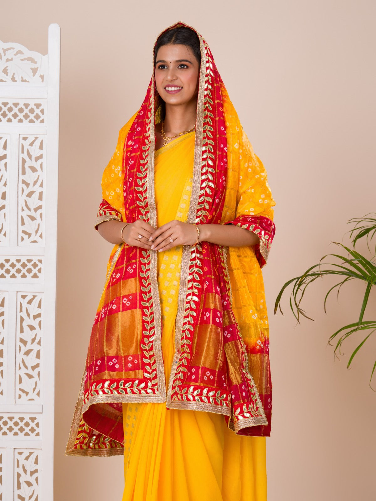 A traditional Rajasthani Bandhani Chunri dupatta in yellow and red with a gotapatti border, paired with a matching gharchola silk pomcha.