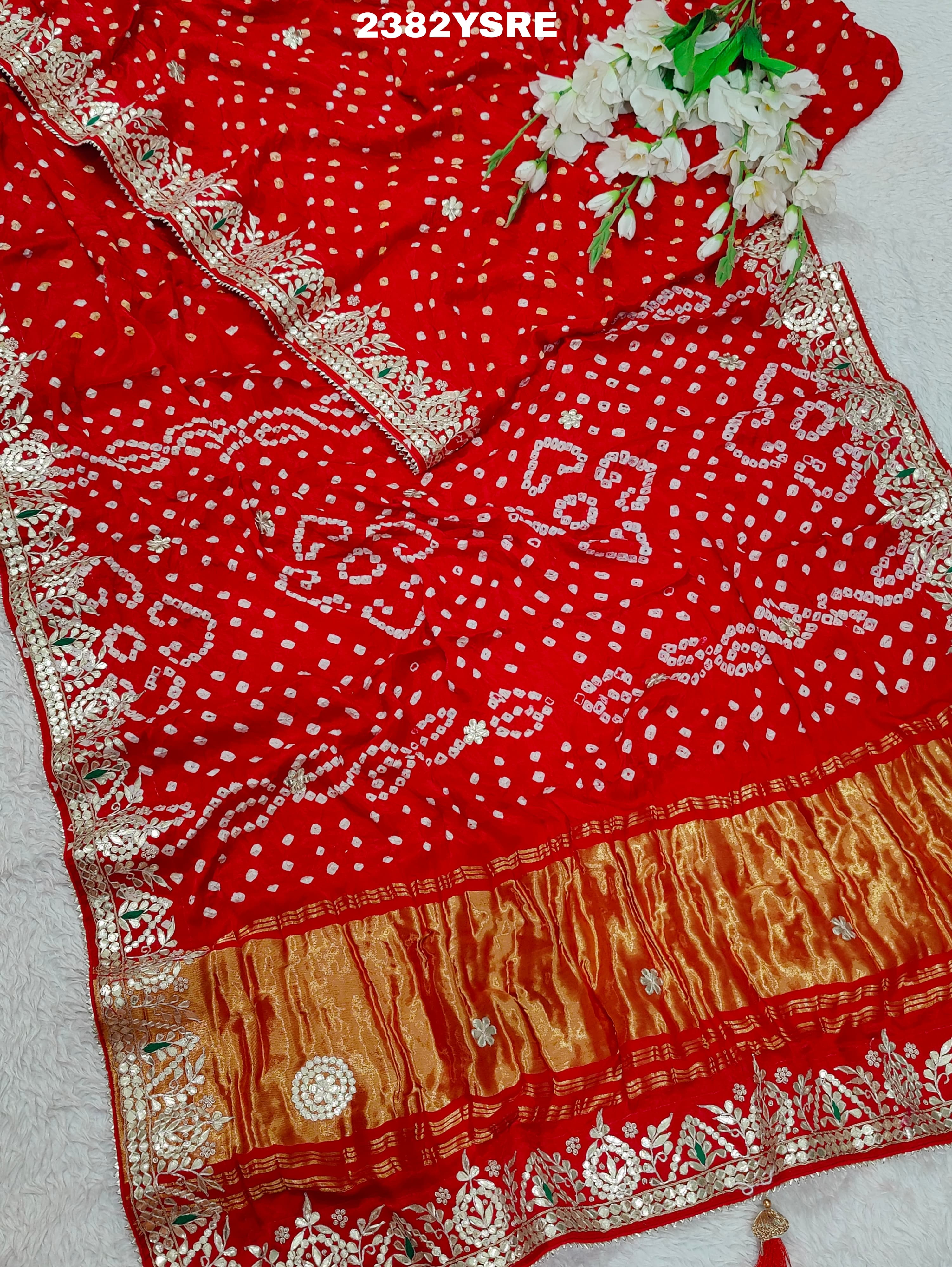 A red saree with white bandhani (dot) pattern and gotapatti border,