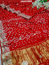 A red saree with white bandhani (dot) pattern and gotapatti border,