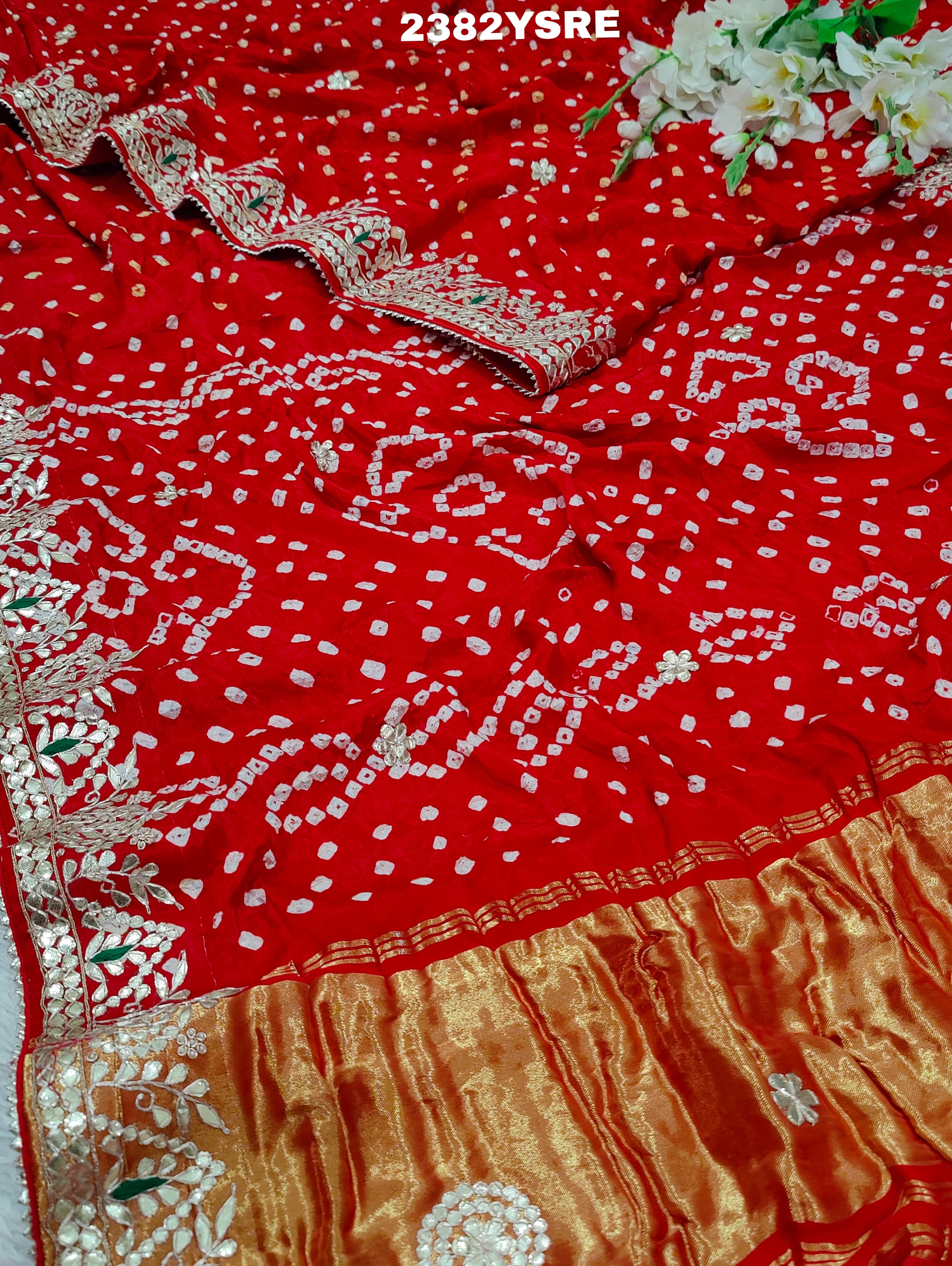 A red saree with white bandhani (dot) pattern and gotapatti border,