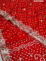 A red saree with white bandhani (dot) pattern and gotapatti border,