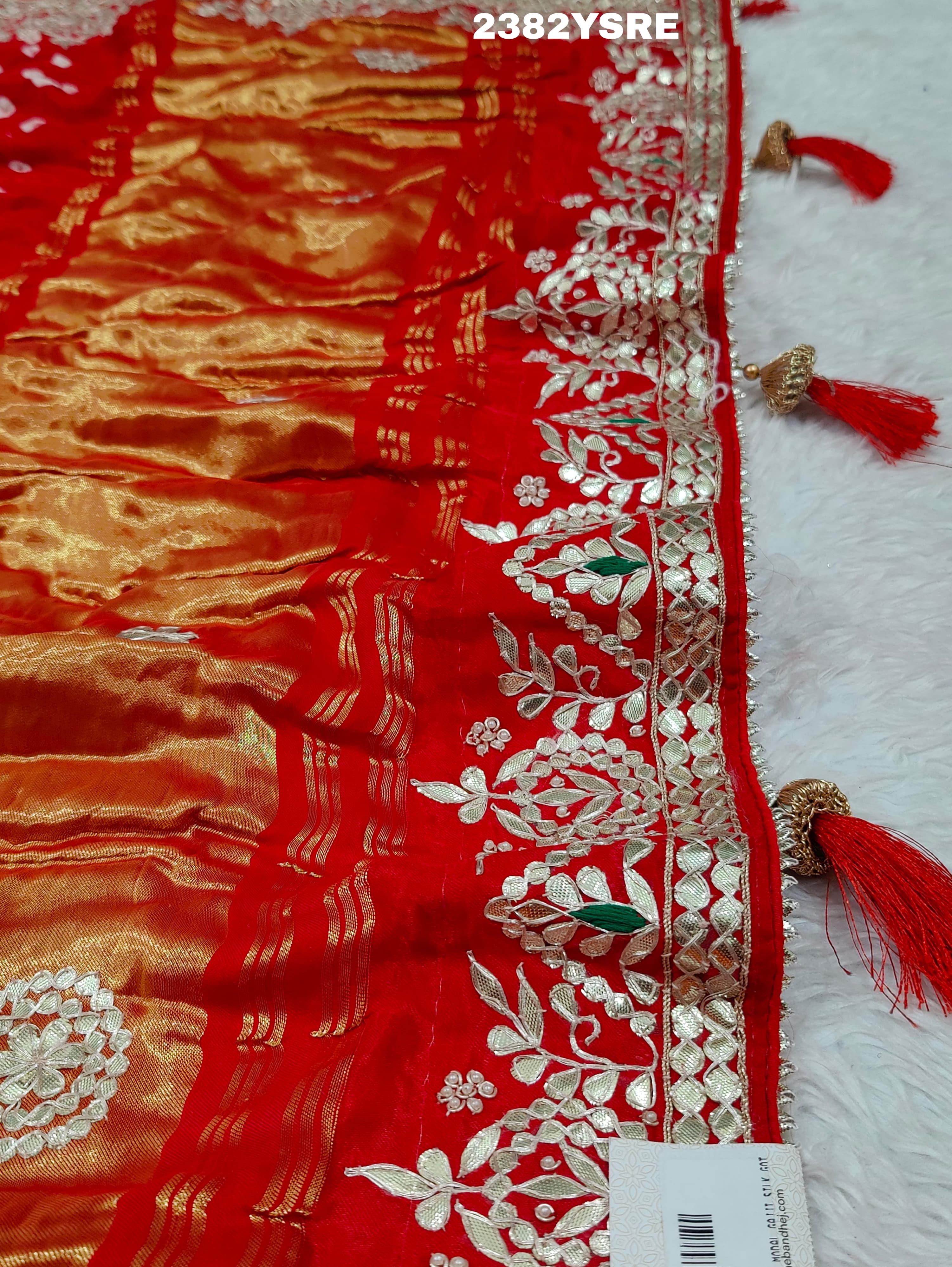 A red saree with white bandhani (dot) pattern and gotapatti border,