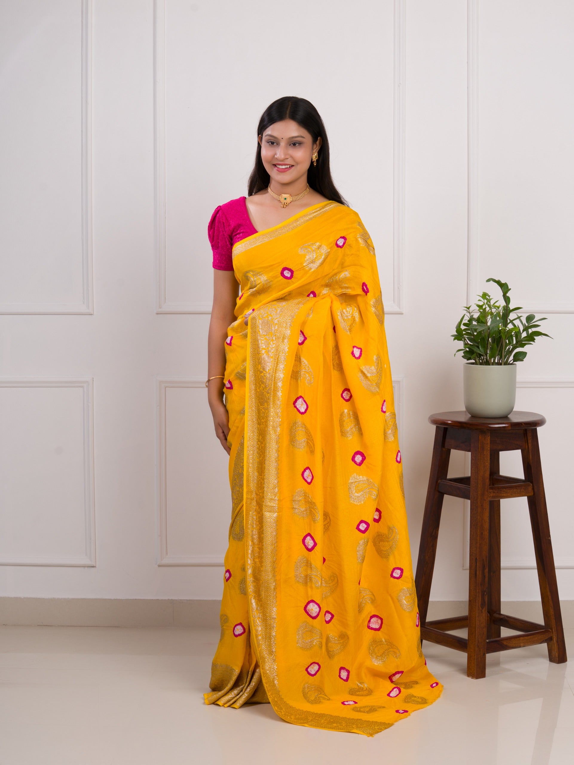 A yellow saree with pink patterns with Dola Silk Bandhani Zari Weaving Work