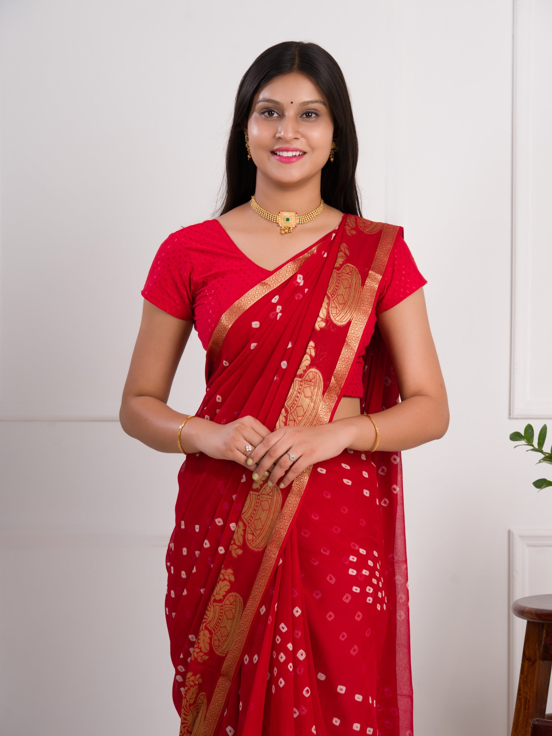 A red saree with gold patternsin Georgette Bandhani Style Saree