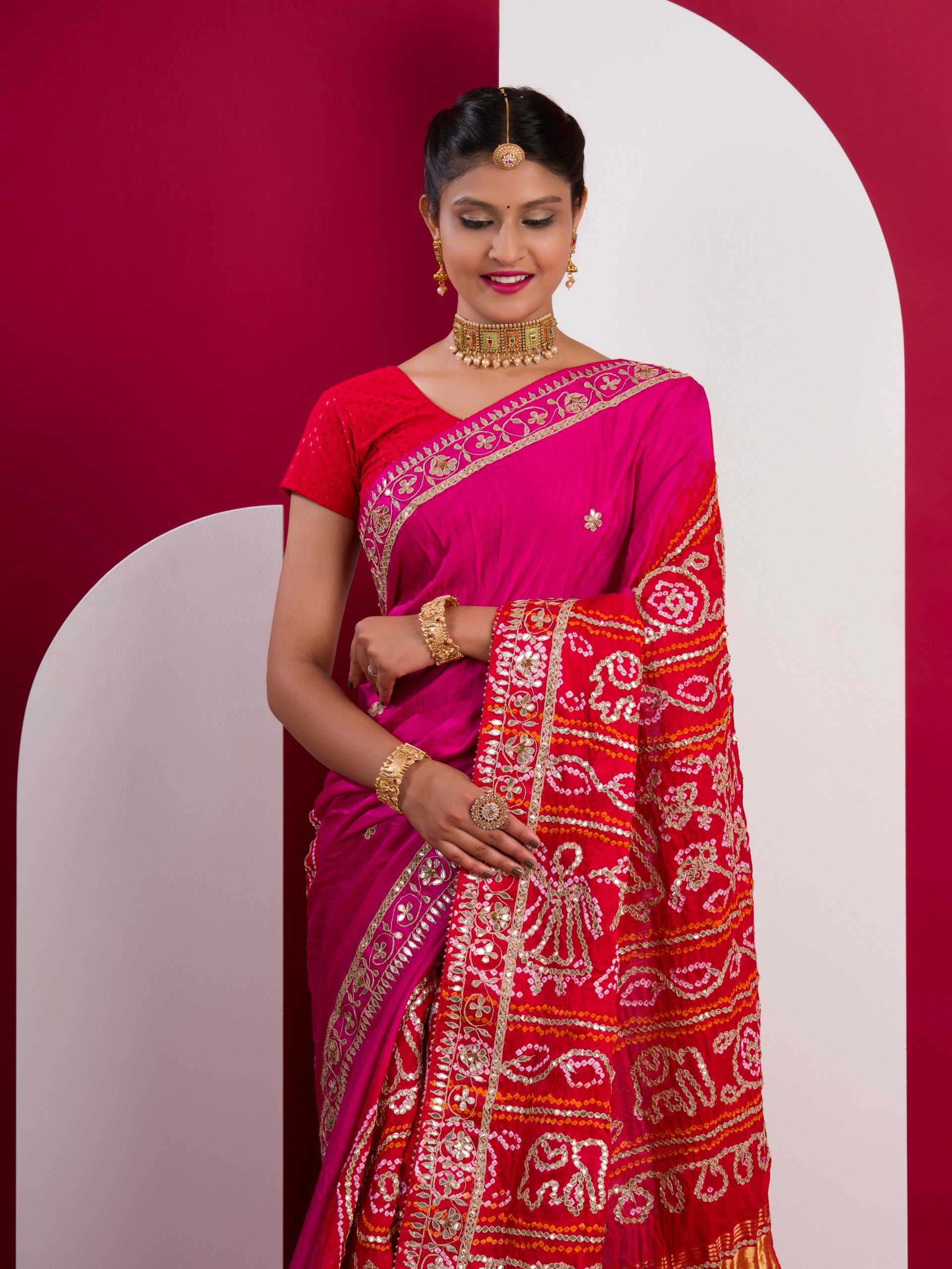 A pink saree with a red and gold border
