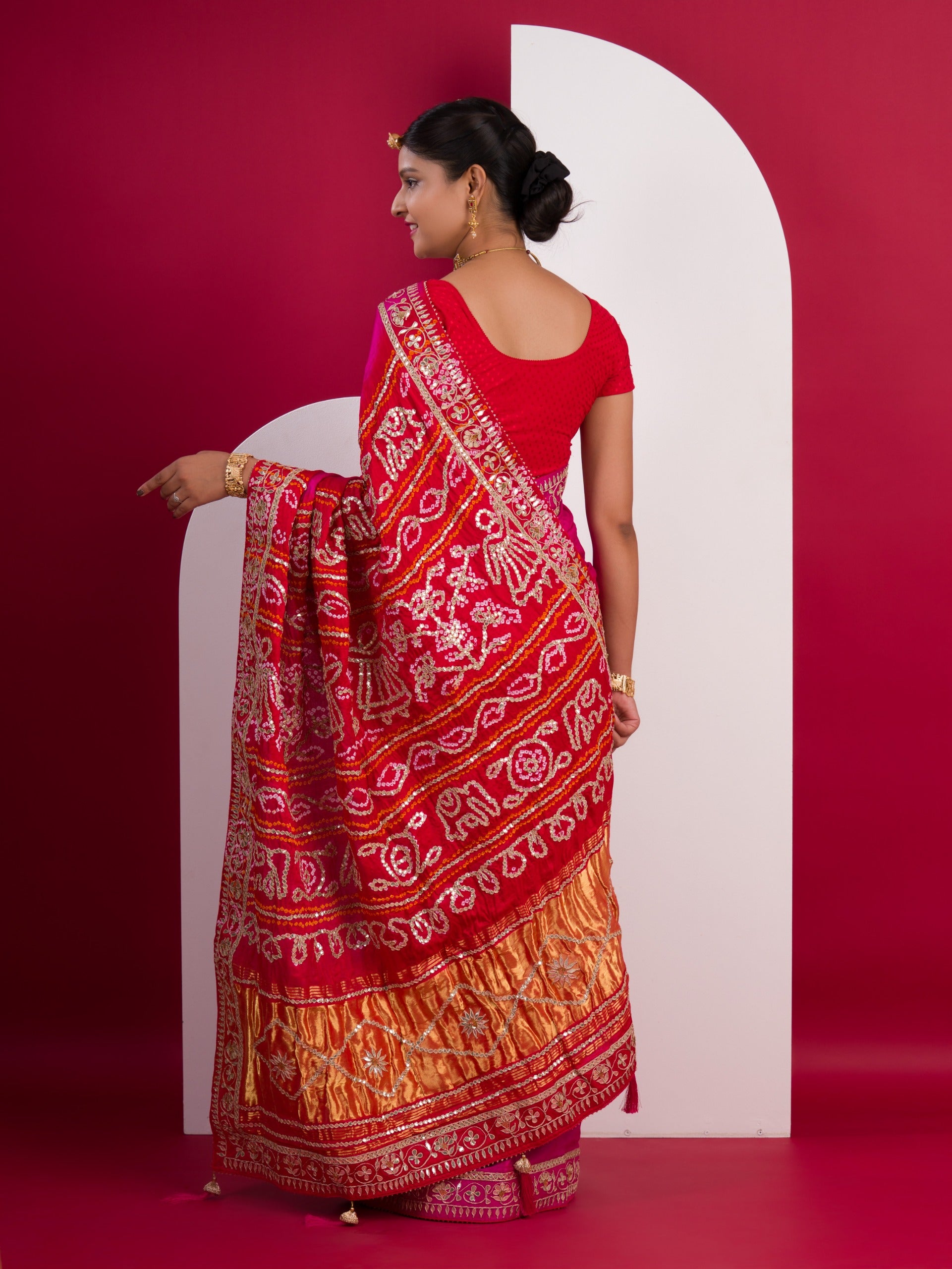 A pink saree with a red and gold border