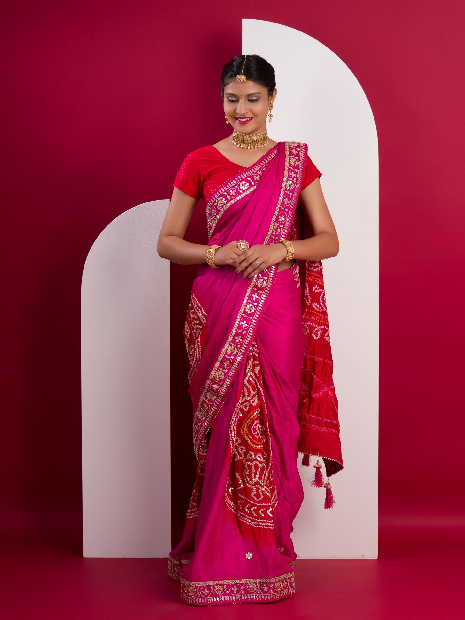 A pink saree with a red and gold border