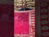 A pink and orange bandhani saree with a zari border