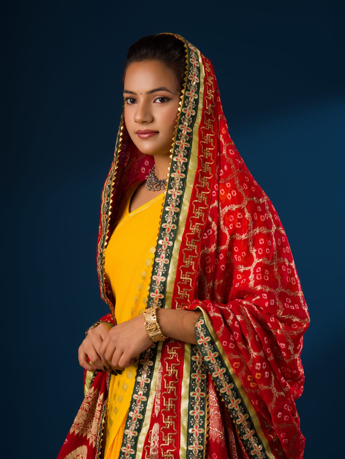A woman modeling a red and yellow Banarasi Ojaria Chunri Piliya dupatta with a geometric pattern.