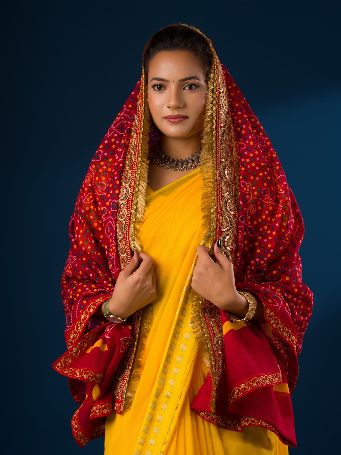 A woman modeling a red and yellow traditional dupatta with embroidery border