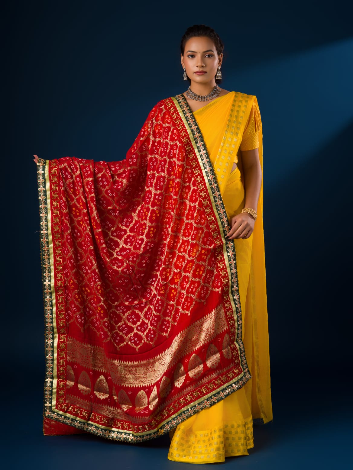 A woman modeling a red and yellow Banarasi Ojaria Chunri Piliya dupatta with a geometric pattern.