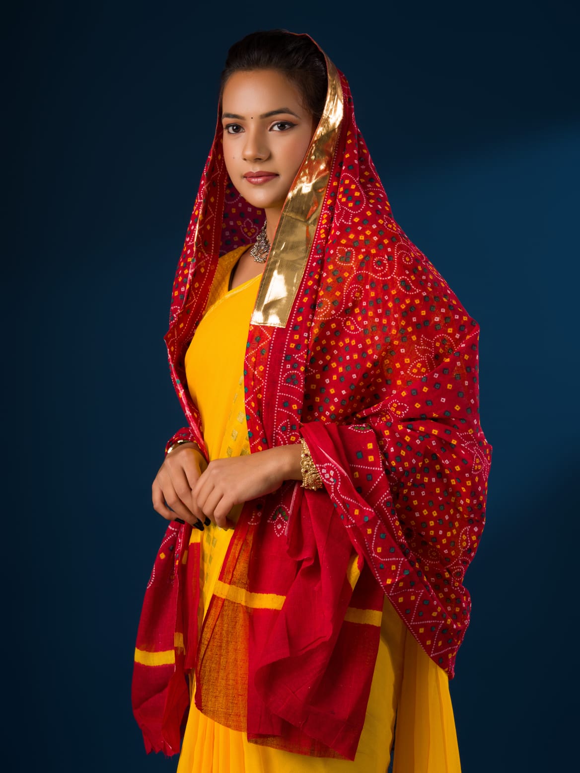 A woman wearing a traditional red and yellow dupatta with a geometric pattern