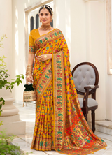 A traditional mustard yellow saree with a floral pattern and a red border, accompanied by a matching blouse piece.