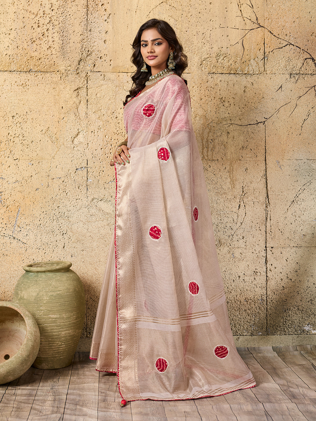 A white saree with red beads work and cutdana embellishments.