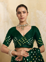 A bottle green saree with bandhani print and lagdi patola pallu, alongside a blouse piece.