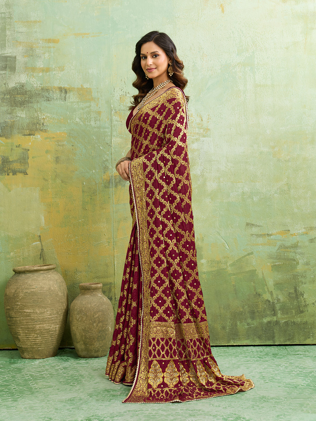  A maroon and gold Banarasi silk saree with heavy zari work (embroidery) and mirror handwork. The saree is traditional wear, likely used for festive or bridal occasions.