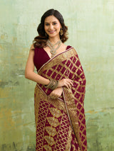  A maroon and gold Banarasi silk saree with heavy zari work (embroidery) and mirror handwork. The saree is traditional wear, likely used for festive or bridal occasions.