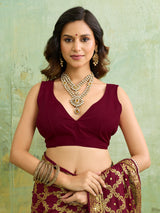  A maroon and gold Banarasi silk saree with heavy zari work (embroidery) and mirror handwork. The saree is traditional wear, likely used for festive or bridal occasions.