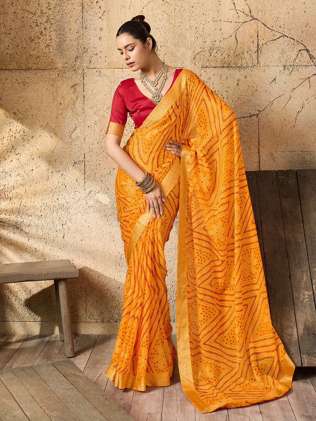A yellow bandhani style chiffon georgette saree with a red blouse piece under 1000