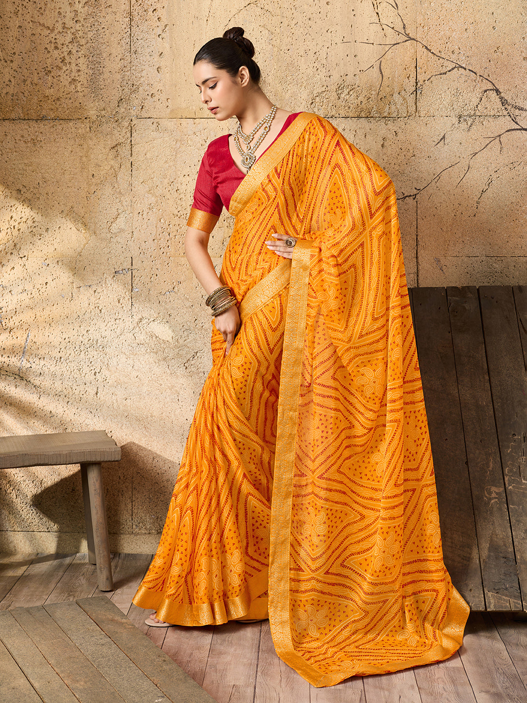 A yellow bandhani style chiffon georgette saree with a red blouse piece under 1000