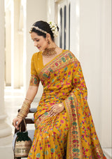  A traditional mustard yellow saree with a floral pattern and a red border, accompanied by a matching blouse piece.