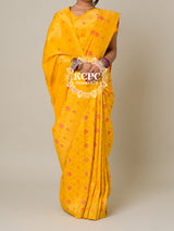 A yellow banarasi silk saree with floral patterns and zari embellishments.