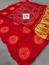 A red silk bandhani saree with yellow zari embellishments 