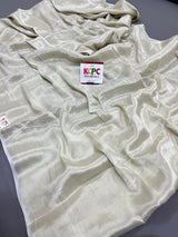 A cream-colored georgette saree draped over a surface, featuring a zari weaving pattern 