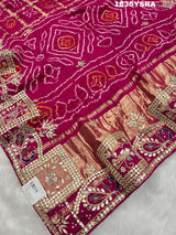 A pink and red silk saree with gota patti work and a floral embellishment 