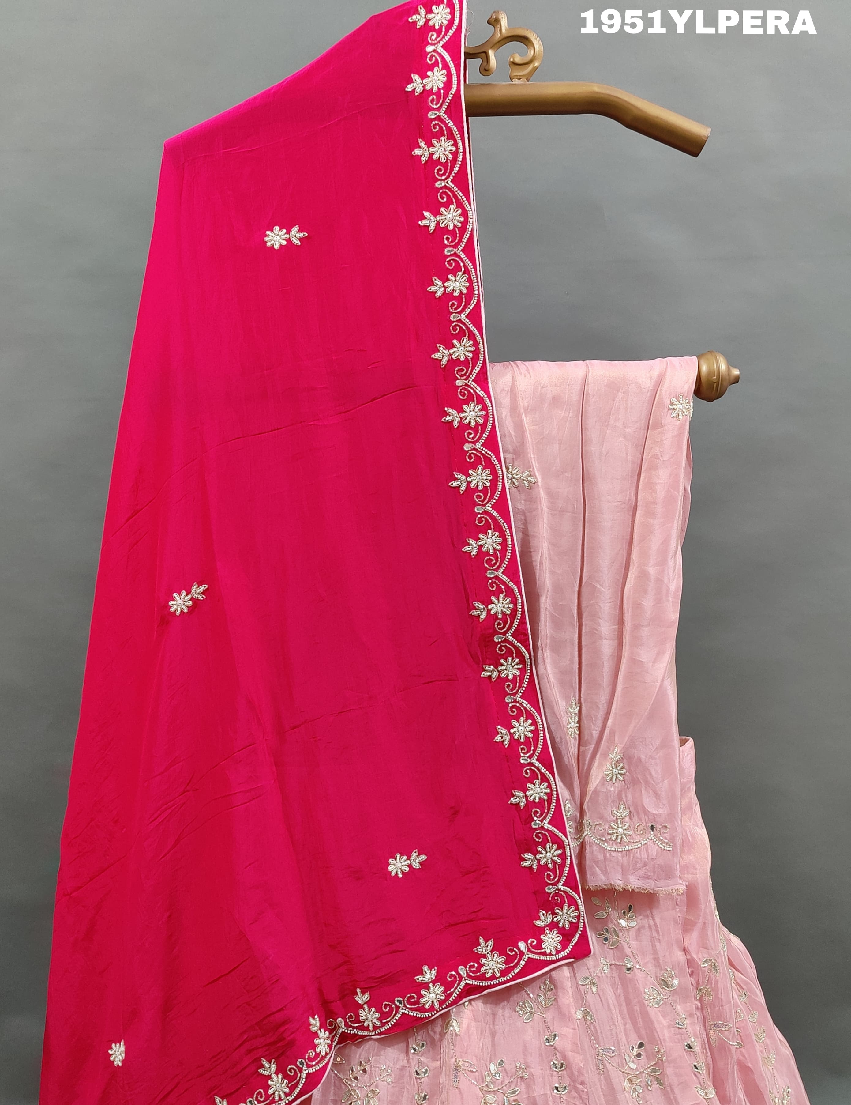 A pink traditional lehenga set with white beadwork and a red dupatta 