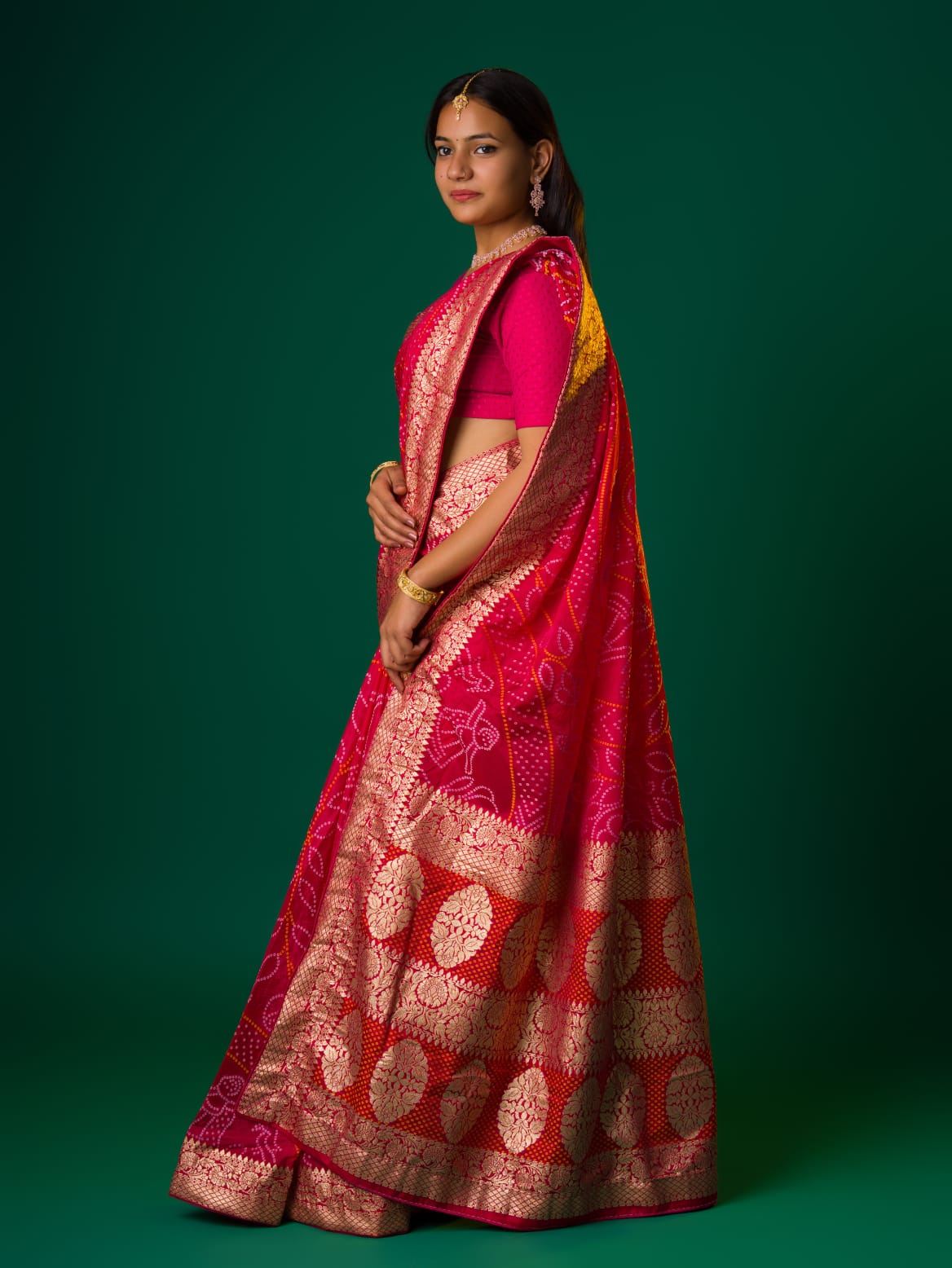 A pink and orange bandhani saree with a zari border