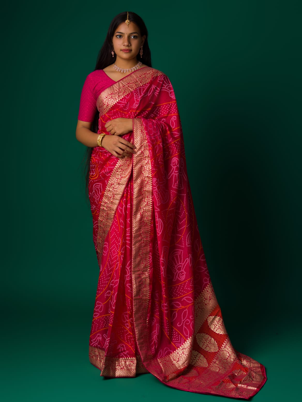 A pink and orange bandhani saree with a zari border