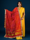 A woman in a traditional yellow attire is holding a red and yellow Bandhani silk chunri with floral patterns and a border.
