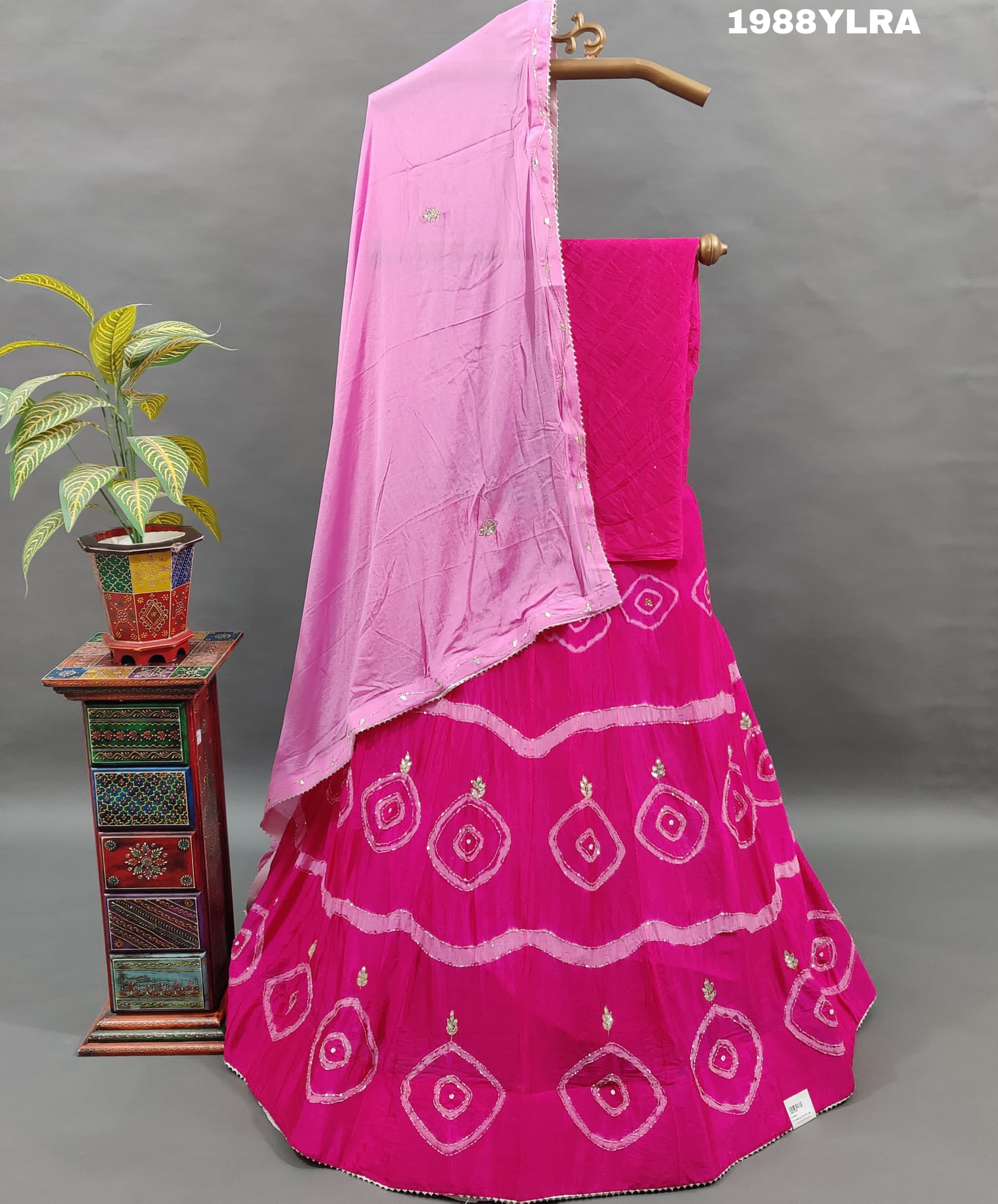 A traditional wear lehenga set with pink and white color bandhani style