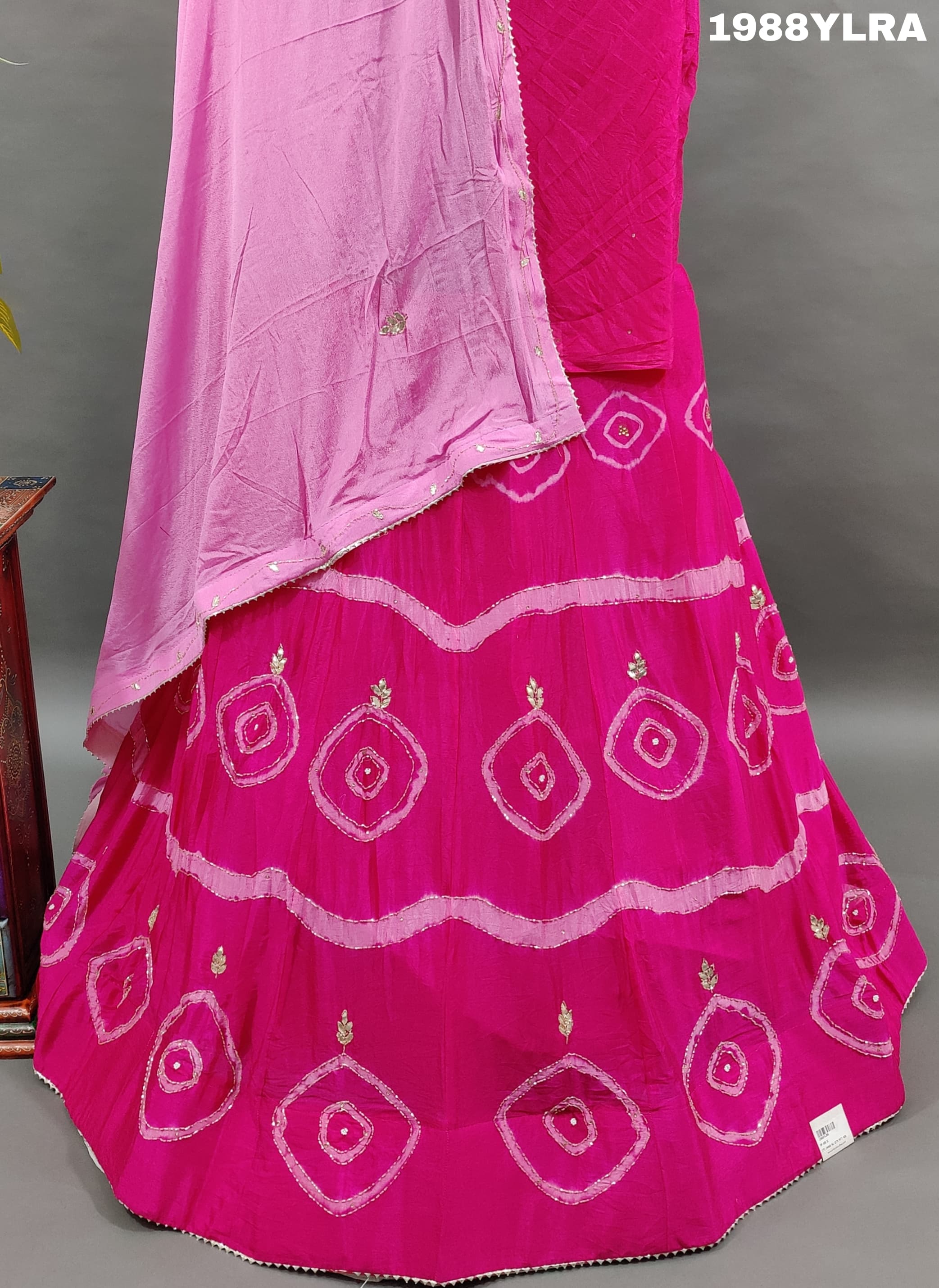 A traditional wear lehenga set with pink and white color bandhani style