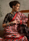 A traditional saree with a geometric ajrak print in red and black colors