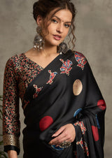 A black silk saree with red and blue ajrak print design and a golden border.