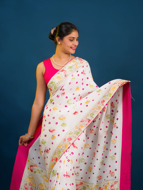 A Chinon silk saree with a Kalamkari style pattern, featuring a white base with multicolored floral designs and zari weaving details