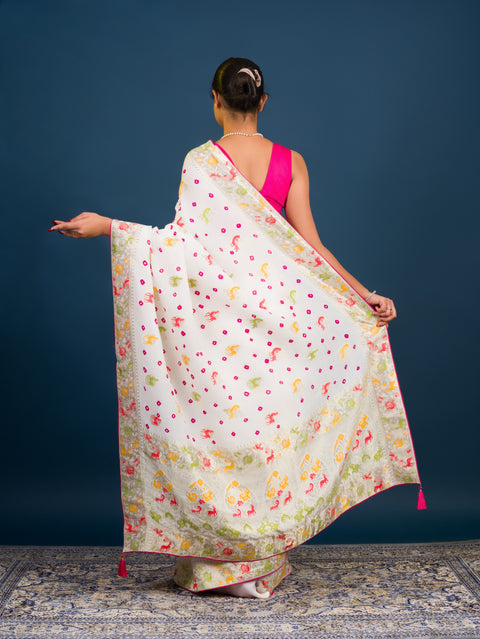 A Chinon silk saree with a Kalamkari style pattern, featuring a white base with multicolored floral designs and zari weaving details