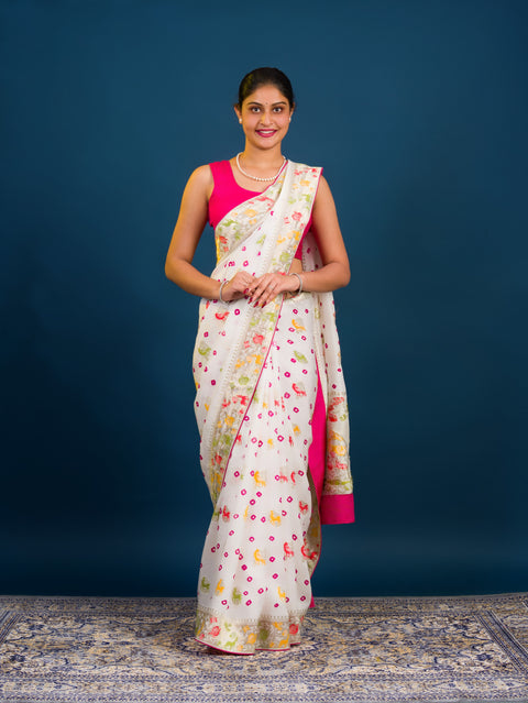 A Chinon silk saree with a Kalamkari style pattern, featuring a white base with multicolored floral designs and zari weaving details