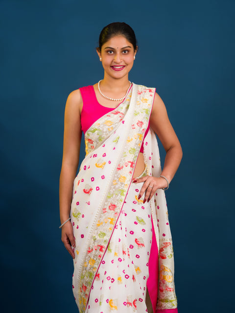 A Chinon silk saree with a Kalamkari style pattern, featuring a white base with multicolored floral designs and zari weaving details