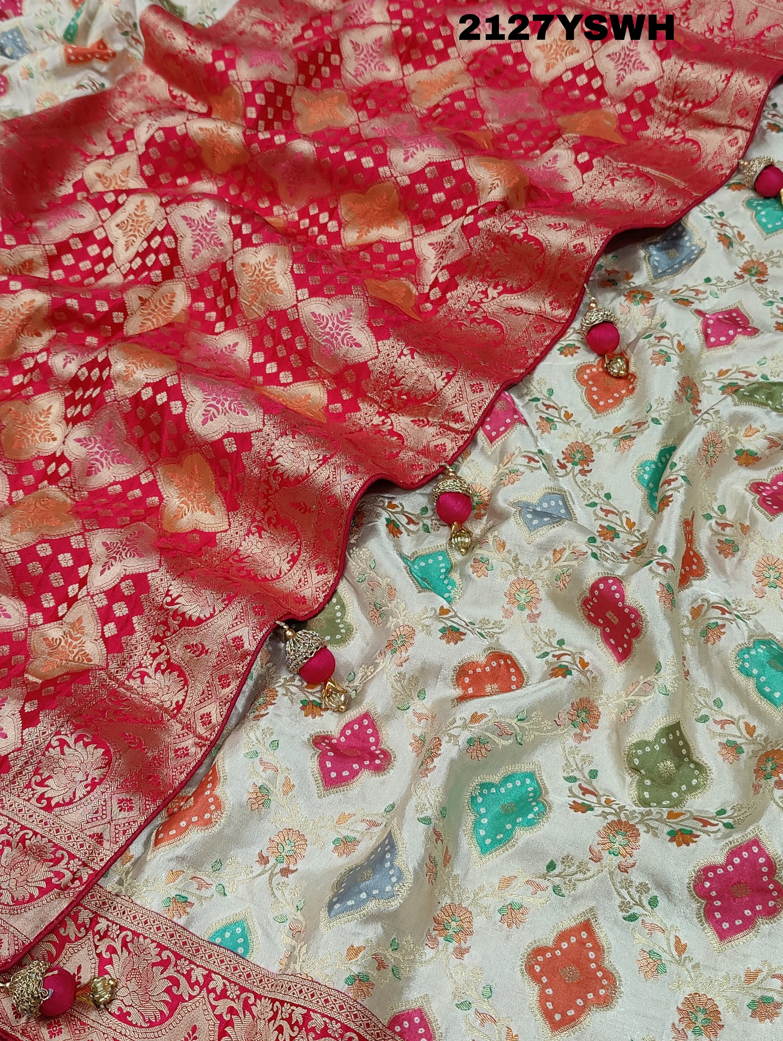 A Banarasi silk saree with a Meenakari pattern featuring a cream body with multicolor floral designs and a red border.