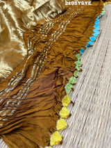 A brown and yellow silk saree with bandhani style dots and a metallic border.
