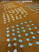 A brown and yellow silk saree with bandhani style dots and a metallic border.