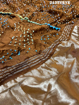 A brown and yellow silk saree with bandhani style dots and a metallic border.